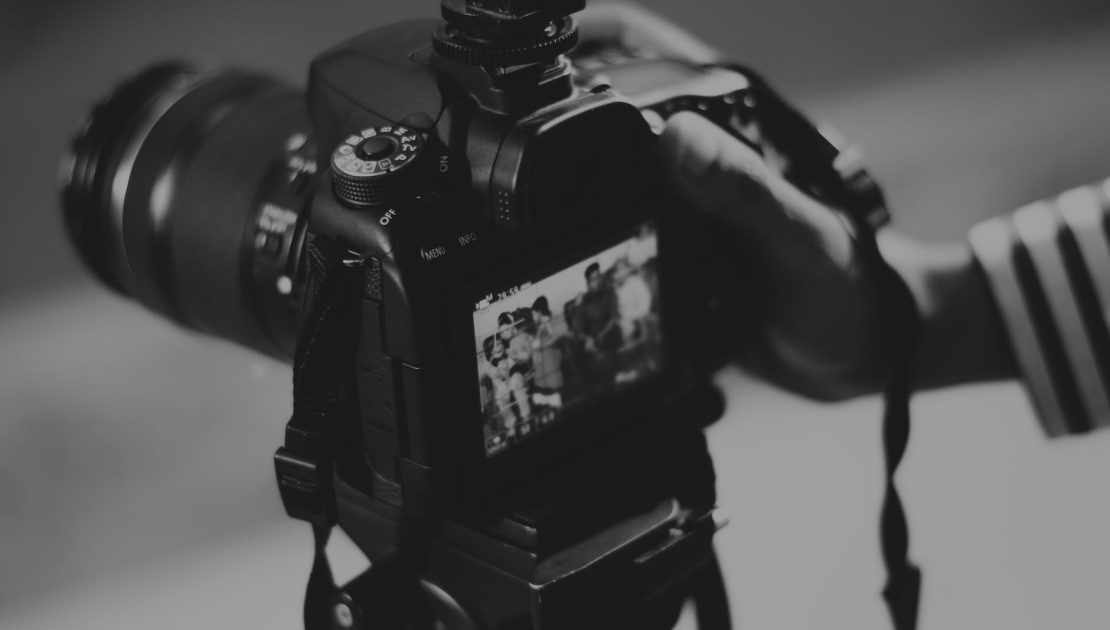 grayscale photography of person holding black dslr camera