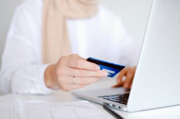 oseba v beli srajci z dolgimi rokavi, ki drži kreditno kartico