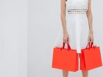 raccolto donna irriconoscibile che trasporta borse della spesa rosse in studio